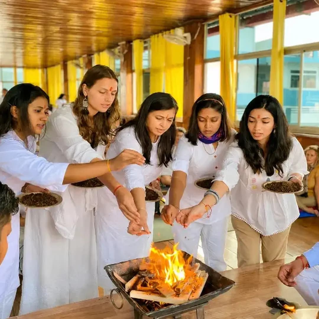 Students in white making offerings at a fire ceremony